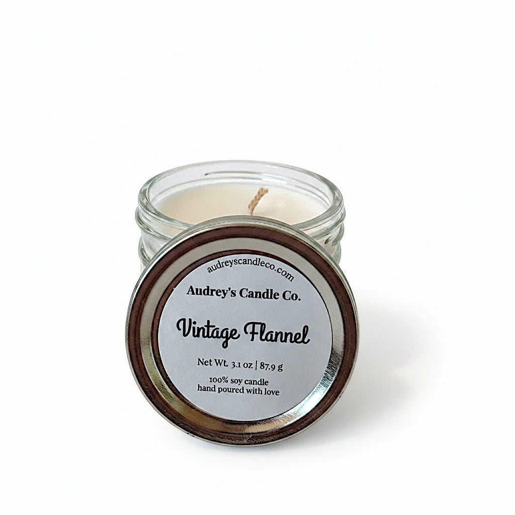 Audrey's Candle Co. Vintage Flannel soy candle in a small glass jar with a metal lid, featuring a clean scent label.